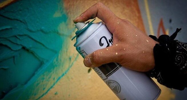 men spray painting on wall