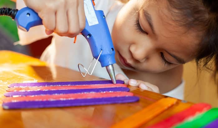 kids using hot glue on painted wooden sticks for craft project-passionthursday.com